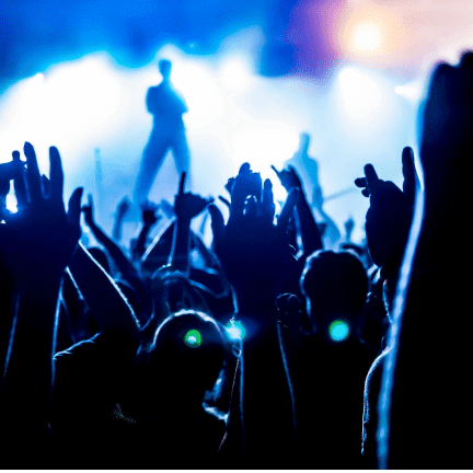 A crowd of people at an event with their hands in the air.